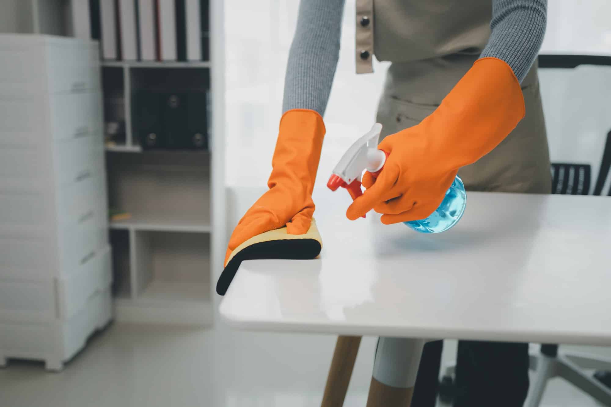 Asian female cleaner wiping down tables with cleaning spray, the housekeeper is cleaning the work de